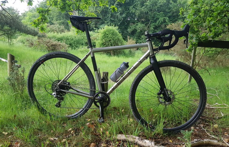 Reilly Gradient with Maxxis Rambler tyres leaning against a fence at the edge of a clearing in Thetford Forest.