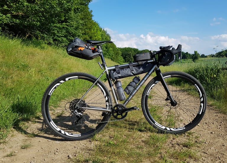 Reilly Gradient loaded for bikepacking with seat pack, frame bag and ENVE carbon wheels on a gravel track.