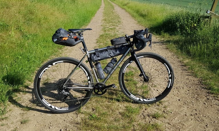 Gravel bike loaded with an Ortlieb seat pack and frame pack, parked on a grassy track in the Peak District.