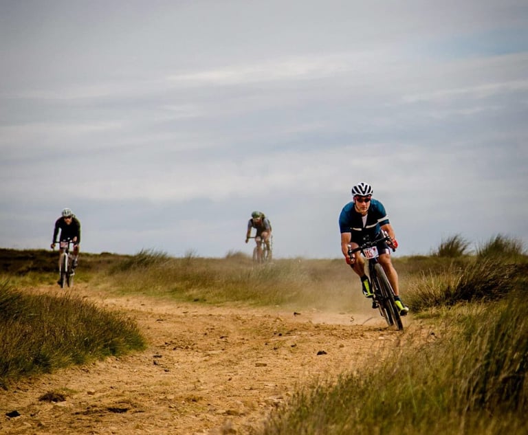 Three riders speed along a dusty gravel track across open moorland at Yorkshire True Grit.