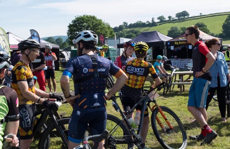 Riders in team kit chat among the trade stands and tents at the Gritfest event village.