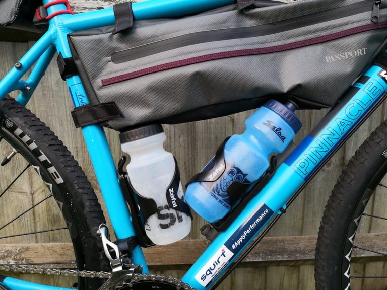 Zefal Wiiz cages hold a clear bottle and a blue bottle beneath the Passport frame bag on the test bike.