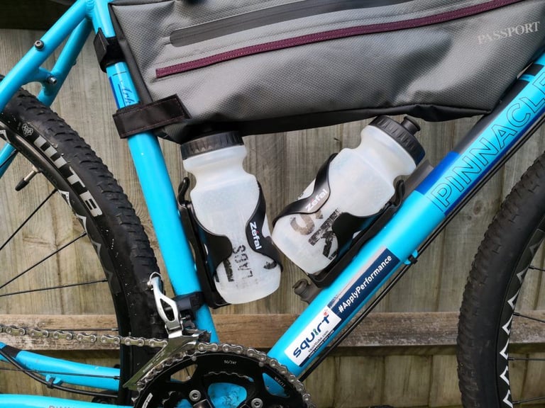 Zefal Wiiz cages angle two water bottles out from under a Passport frame bag on a blue bike.