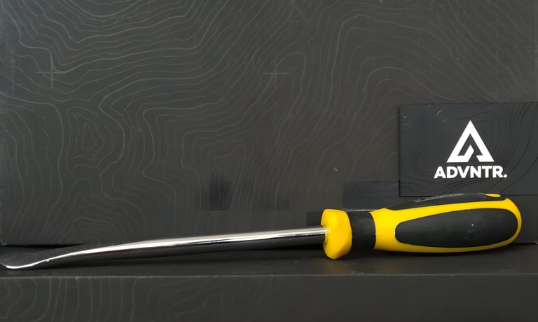 Long workshop tyre lever with a soft yellow and black screwdriver-style handle lying on a dark contour-pattern surface.