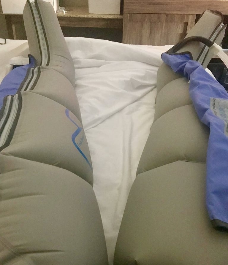 Rider's legs in Elevated Legs inflatable compression sleeves, resting on a bed after the Dirty Kanza 200.