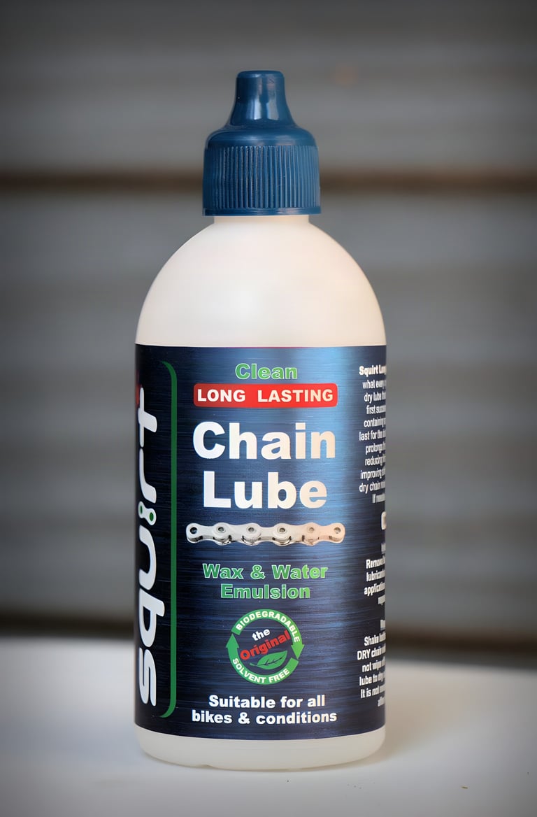 Single bottle of Squirt Long Lasting Chain Lube standing upright with a blue cap against a blurred grey background.