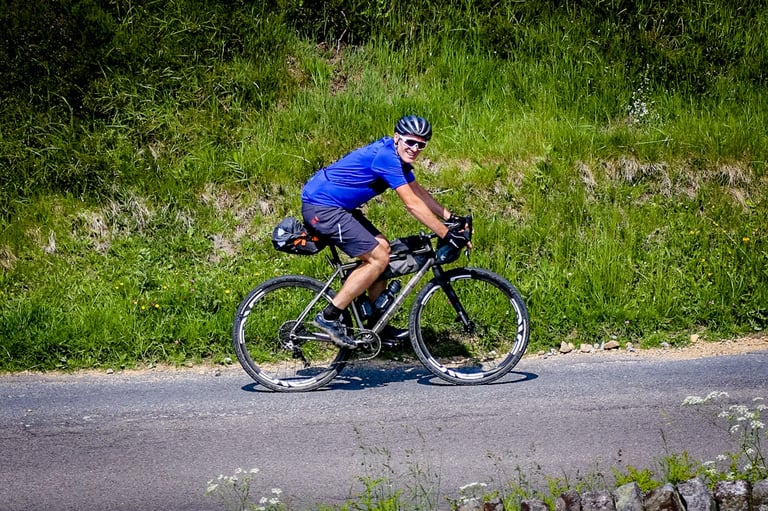 Rider on the Reilly Gradient with seat pack and frame bag rides a road at The Distance in the Peak District.