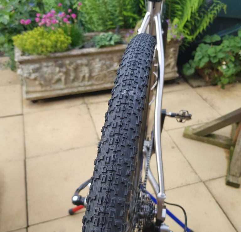 Maxxis Rambler gravel tyre fitted to the rear wheel of a bike standing on a patio, tread facing the camera.