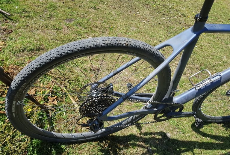 Maxxis Rambler 700x40 tyre on the rear wheel of a blue-grey gravel bike parked on grass.