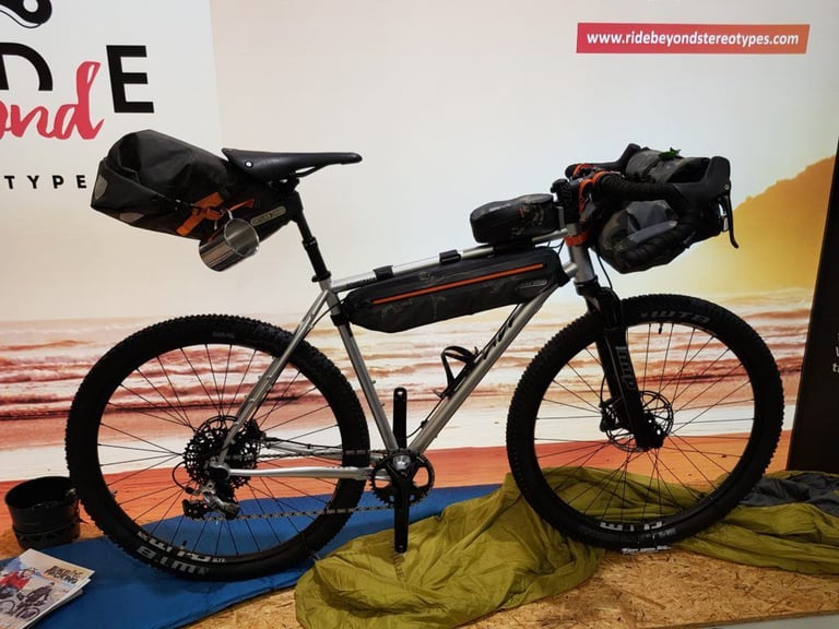 Bombtrack bike carrying Ortlieb saddle, frame and handlebar bags in front of a beach backdrop at Eurobike.