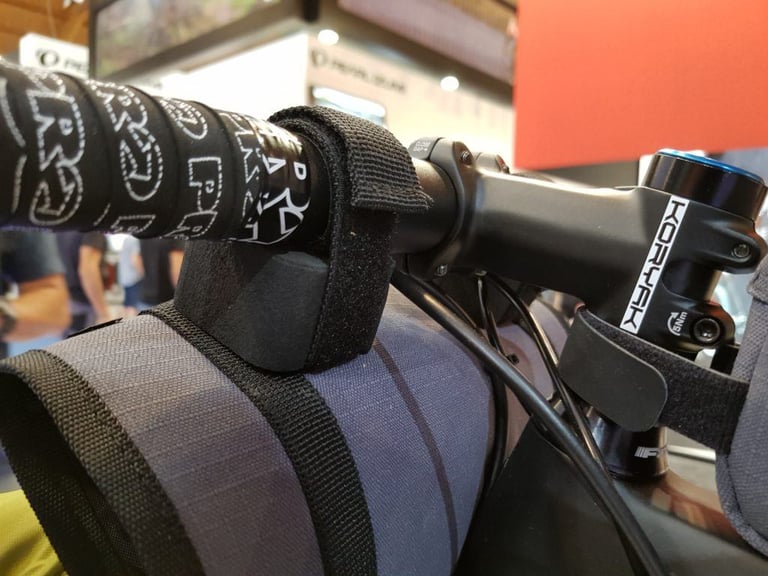 Velcro strap and foam spacer on the PRO Discover handlebar harness, keeping the pack clear of the bars and stem.