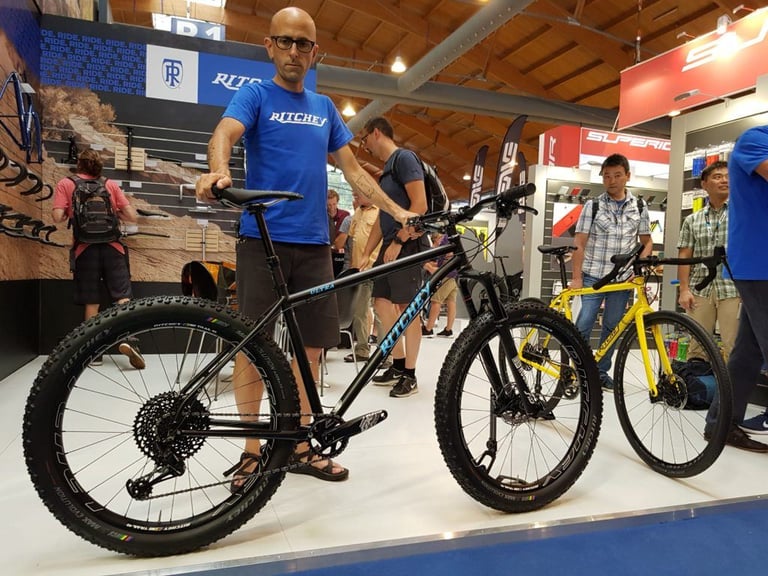 Ritchey Ultra steel hardtail in black with chunky tyres, held up by a stand staffer at Eurobike 2018.