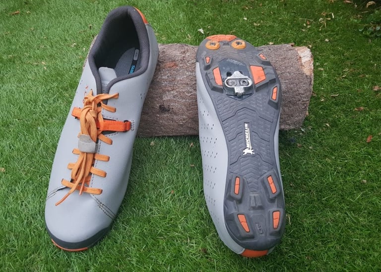 Shimano XC5 shoes, one showing the laces and lace tidy, the other showing the Michelin outsole and SPD cleat.