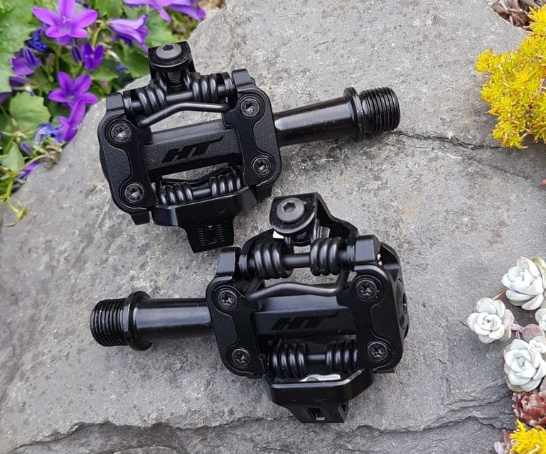 Pair of new HT Components Leopard M1 pedals on a rock, springs and cleat latches showing, before testing began.