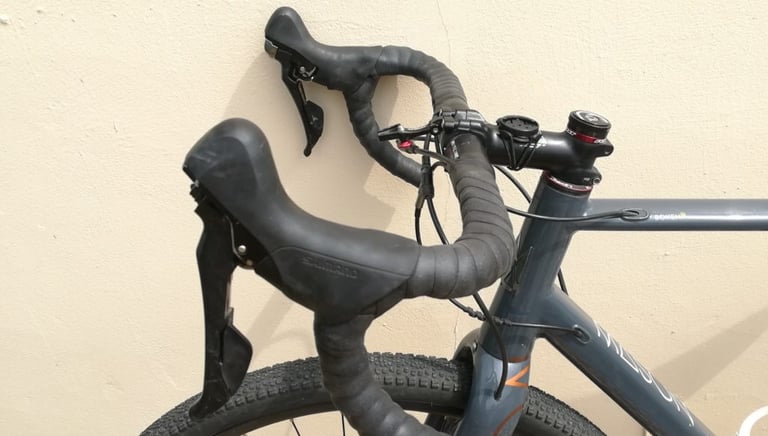 Genetic silicone bar tape wrapped on the drop bars of a Mason Bokeh with Shimano levers, against a pale rendered wall.