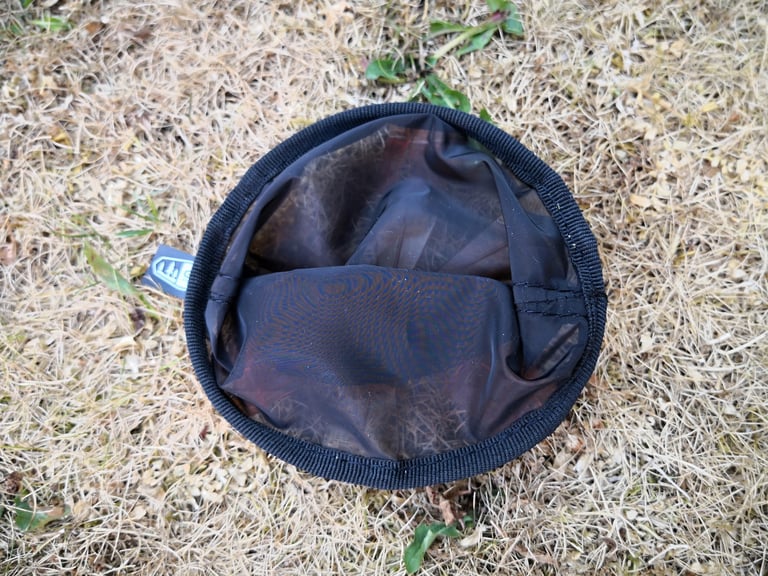 Folded GSI Java Drip filter lying on dry grass, seen from above, small enough to fit a gas canister recess.