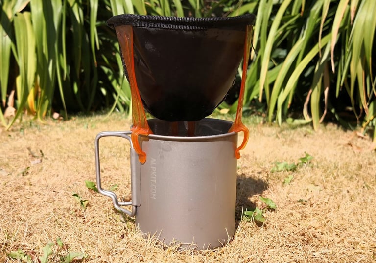 GSI Java Drip filter perched on a titanium mug in sunshine, coffee dripping through into the mug below.