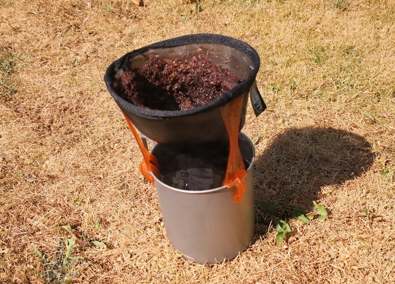 GSI Java Drip filter full of used coffee grounds sitting on a mug, with brewed coffee in the mug beneath.