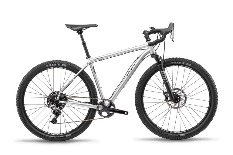 Bombtrack Hook ADV gravel bike in metallic grey with suspension fork, dropper post, drop bars and WTB tyres, side view.