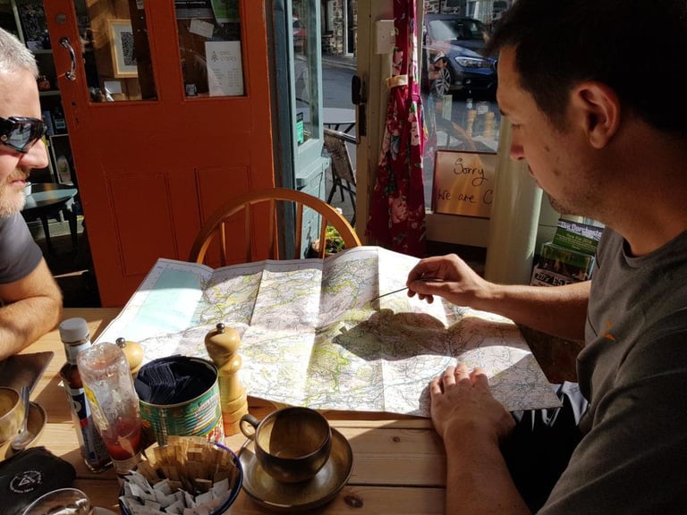 Guide Dave Evans traces the day's route on a folded map spread across a cafe table in Corris.