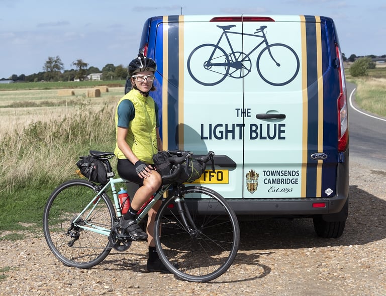 Ede Harrison sits astride her loaded Wolfson beside The Light Blue's van, lettered Townsends Cambridge.