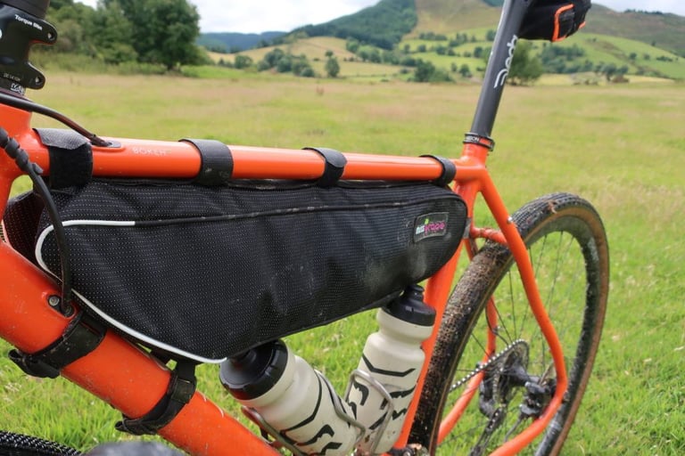 Front of the Miss Grape Internode frame bag with its downtube straps and reflective piping on an orange bike.