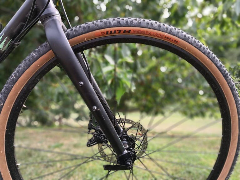 Front wheel of a gravel bike with a tan-wall WTB Resolute 700x42 tyre, seen side-on past the fork.