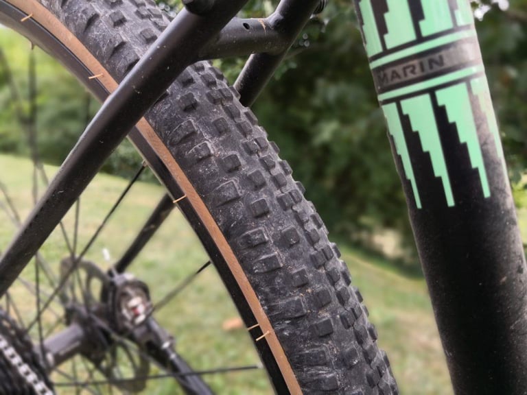 WTB Resolute tread and tan sidewall close up beside a black Marin Four Corners frame tube with a green decal.
