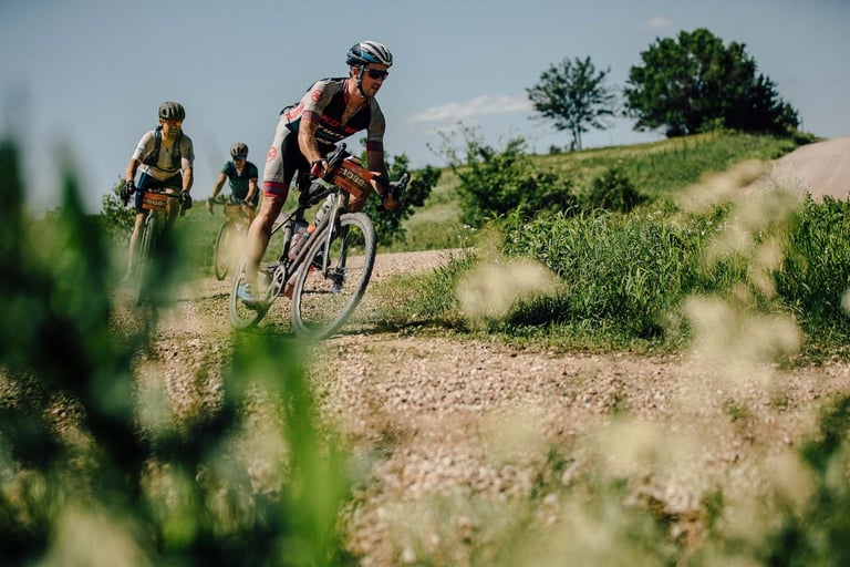 Cory Wallace riding a Kona Libre on a gravel road at Dirty Kanza, with two riders behind him.
