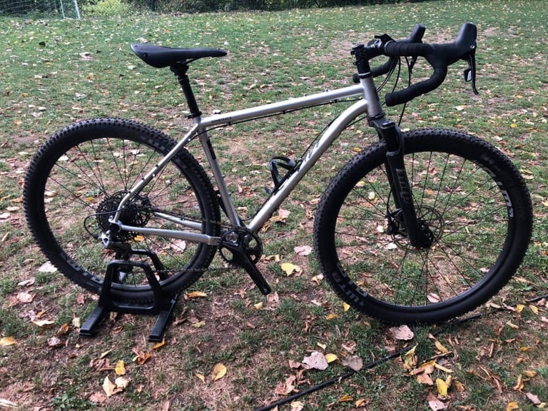 Bombtrack Hook ADV in silver with MRP suspension fork, dropper post and drop bars, standing on grass.
