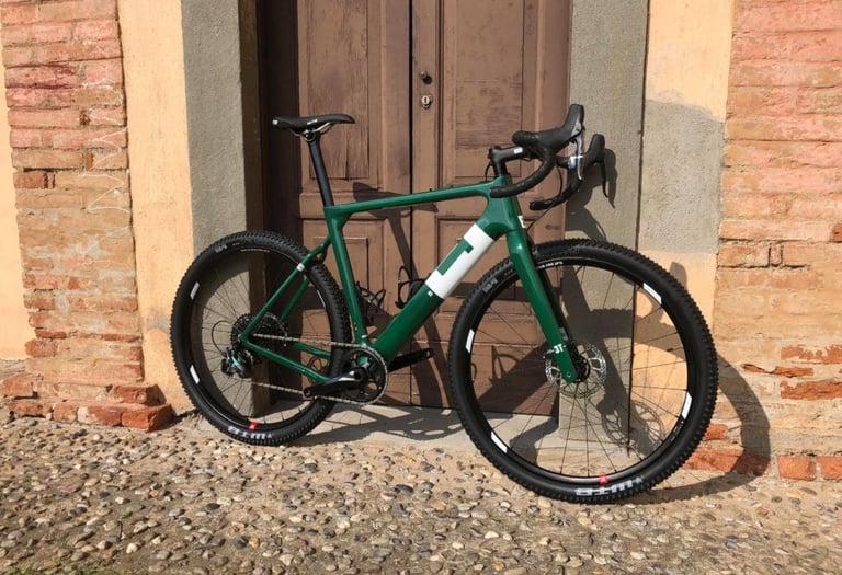 Side view of the green 3T Exploro on cobbles, with WTB mountain bike tyres and a SRAM drivetrain.