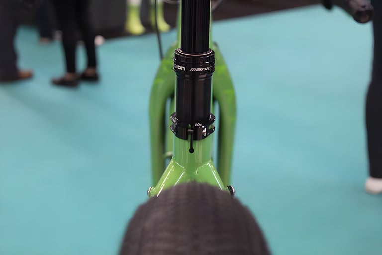 Close-up of a black Manic dropper seatpost and clamp on the green Mason ISO, seen from behind over the rear tyre.