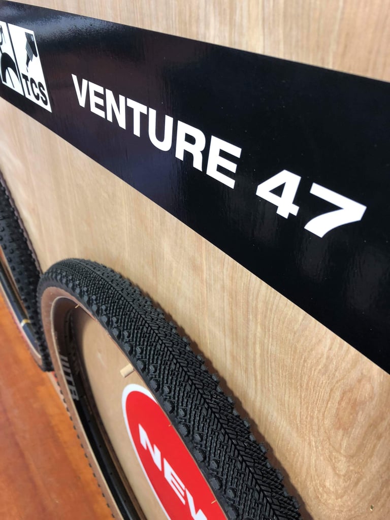 Fine file-tread pattern of the WTB Venture 47 Road Plus tyre below its TCS display board sign.