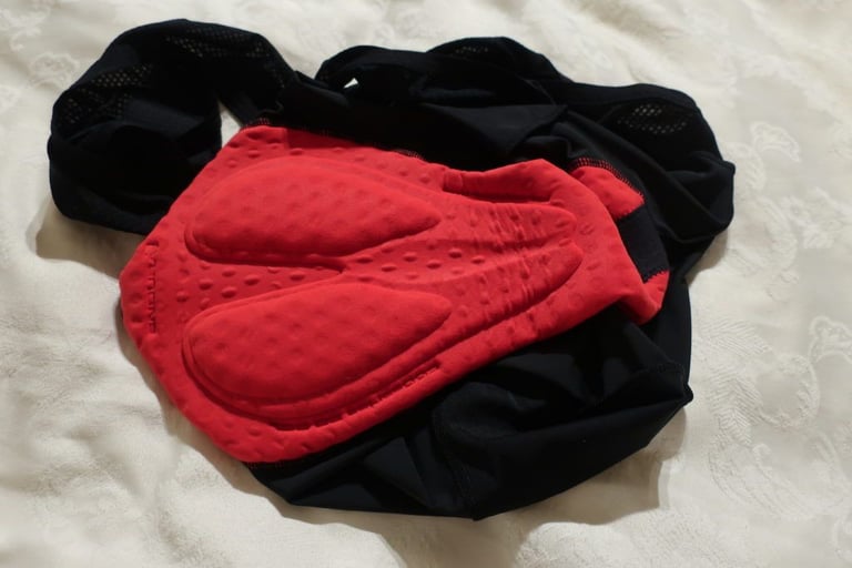 Red Endura 600 Series pad inside the black FS260-Pro bibshorts, laid out on a pale bedspread.