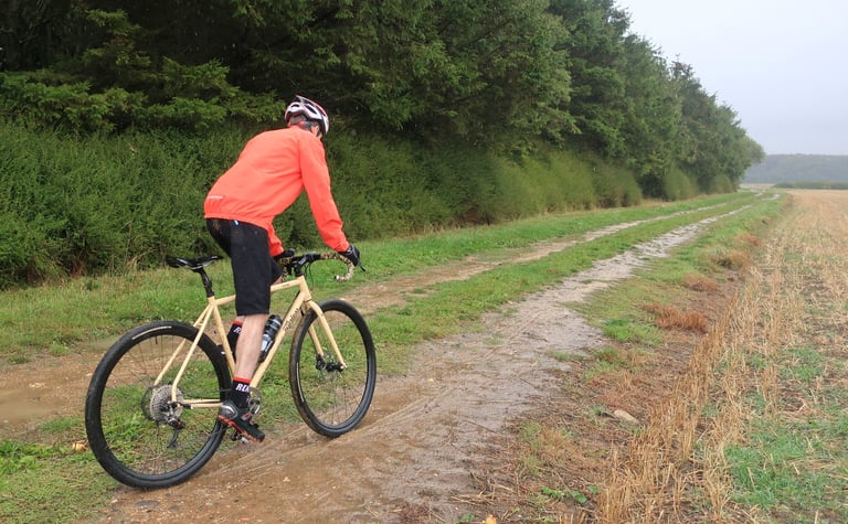 Rider in an orange jacket tests the Halo Vapour GXC wheels on a wet, muddy field-edge track.