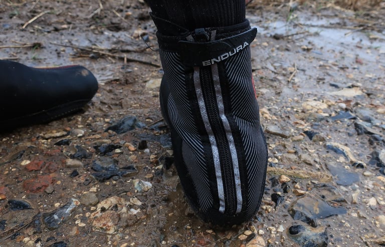 Rear of the Endura Freezing Point overshoe showing the zip with reflective stripes and the wind flap strap.
