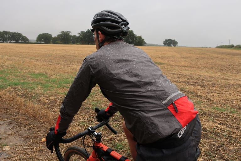 Rear of the Gore C5 Shakedry 1985 Viz jacket with its red zipped pocket and reflective trim, beaded with rain.