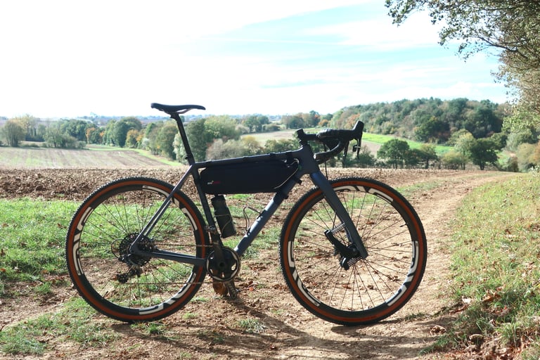 Lauf True Grit built with SRAM Force 1x and a frame bag, parked on a track above autumn countryside.