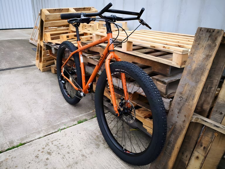 The 2019 Surly ECR 29+ propped against wooden pallets outside a workshop, front wheel and Knard tyre nearest the camera.