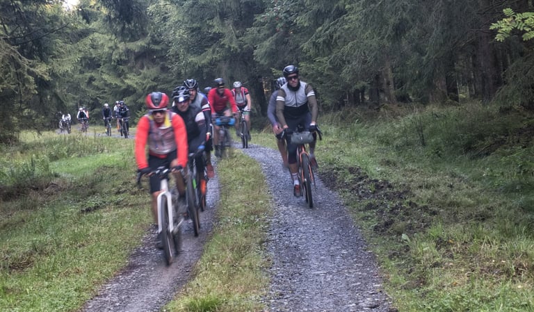 Bunch of Dirty Boar riders on a gravel forest track in the Ardennes in the misty early morning.