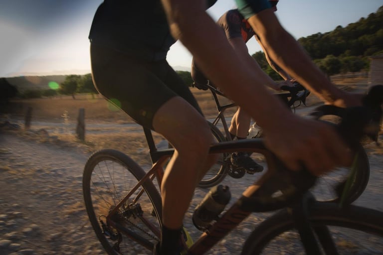 Two riders at speed on a dusty track at sunset, the nearest on a Canyon gravel bike, promoting Toros de Gravel.