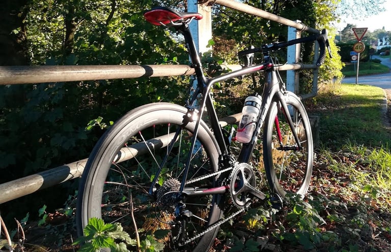 Trek Emonda road bike fitted with Halo Carbaura RC carbon wheels, leant against a railing beside a village road.