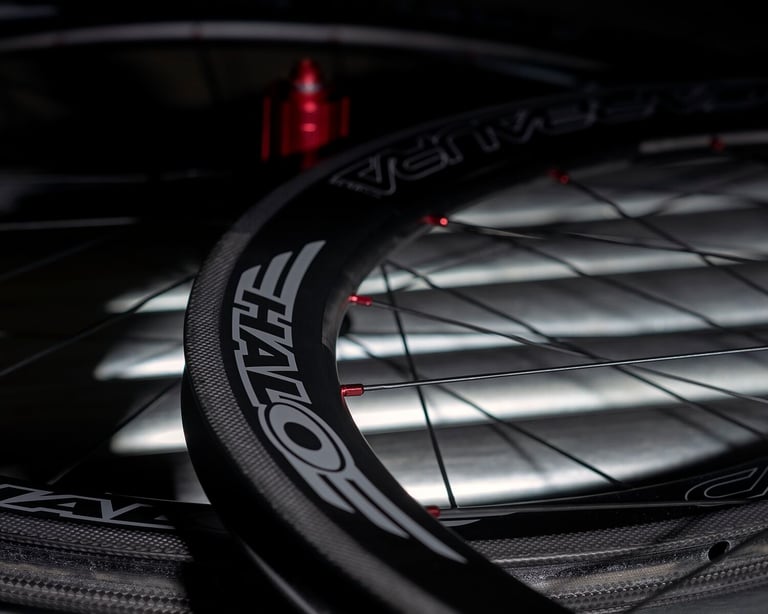 Close-up of the Halo logo and red spoke nipples on a Carbaura RC carbon rim, with a red hub behind.