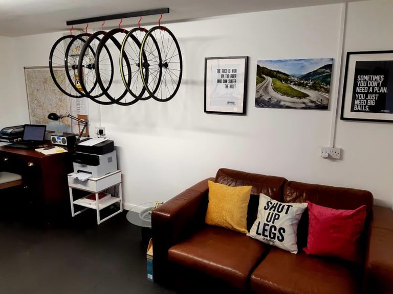 Empty leather sofa with a Shut Up Legs cushion below wheels hung from a rail at Sharp Precision Wheels.