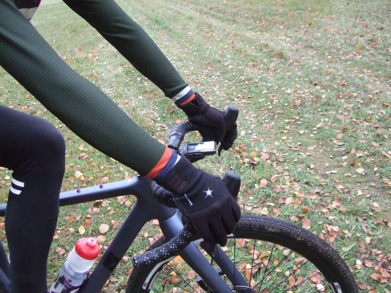 Close-up of Chapeau Club Thermal Jersey sleeves and cuffs meeting winter gloves on a gravel bike's handlebar.