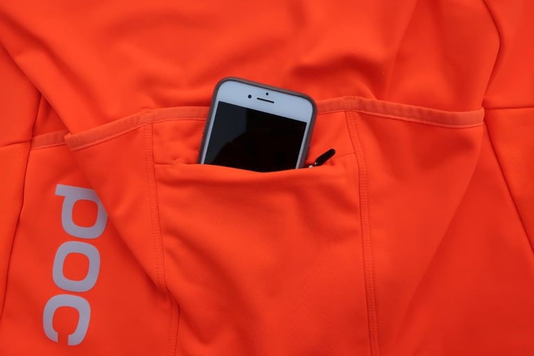 Rear pocket of the POC AVIP jersey holding a phone, beside the reflective POC logo.