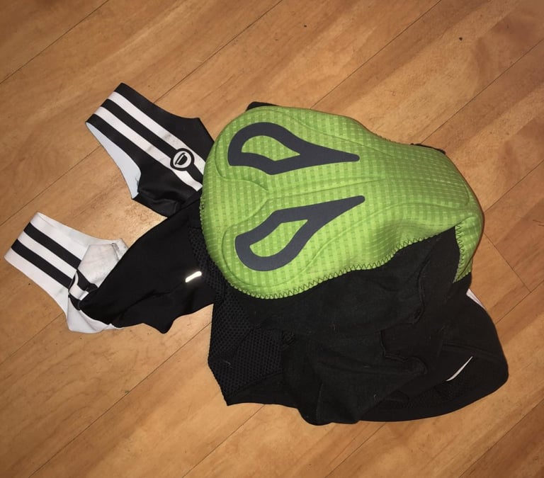 Elastic Interface chamois pad in the Chapeau bibtights, green with grey panels, with the ankle stirrups beside it.