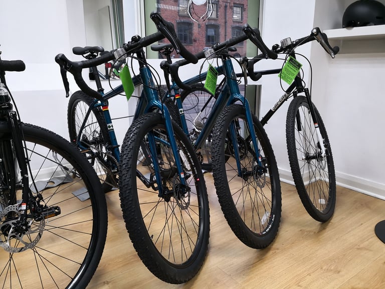 Row of drop-bar adventure bikes with knobbly tyres on display inside the Keep Pedalling shop in Manchester.