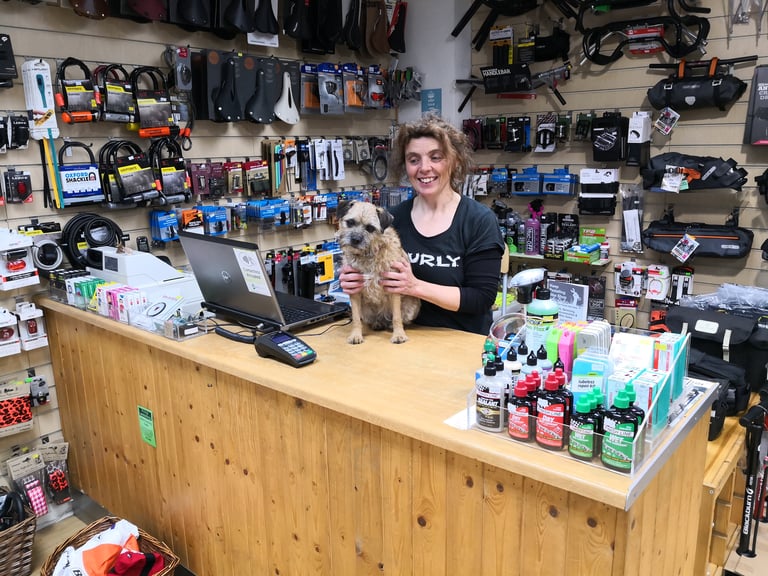Shona of Keep Pedalling holds Olive the Border Terrier on the shop counter in Manchester.