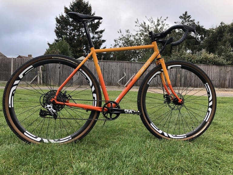 All-City Gorilla Monsoon on 700c carbon wheels with Panaracer Gravel King SK tyres, standing on a lawn.